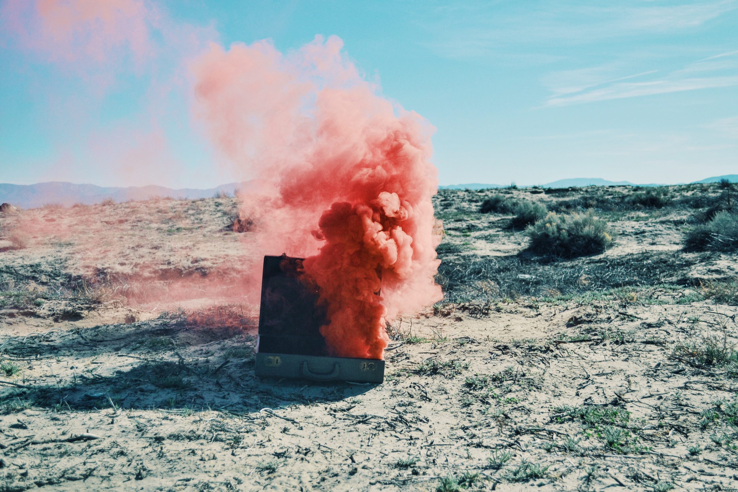 briefcase on the sand with red smoke